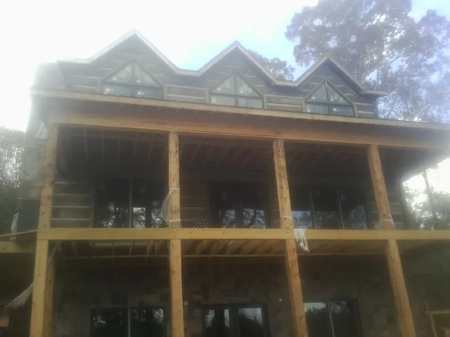 Dormers and porch framing on a large log home under construction — Roof Coating work by our crew in Holt