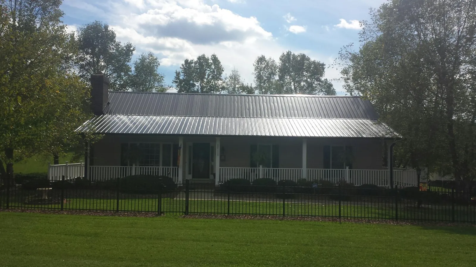 Gray metal roof on a brick ranch with a full width front porch — Gutter Guard Installation work by our crew in Holt